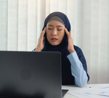 Muslim woman kneaded her head with a hand massage while suffering from a migraine headache.